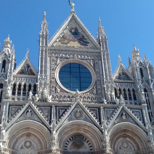 Oberer Teil der Fassade des Doms von Siena vor blauem Himmel