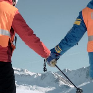 Zwei Hände mit Skistock halten sich vor Bergpanorama