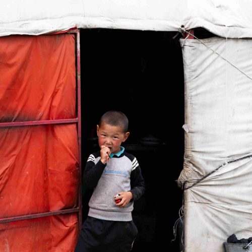 Ein Nomaden-Jungen schaut aus der Tür einer Jurte